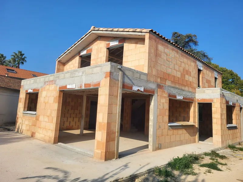 Maison en briques avec garage. Vue du gros œuvre d’une maison avec garage et terrasse couverte.