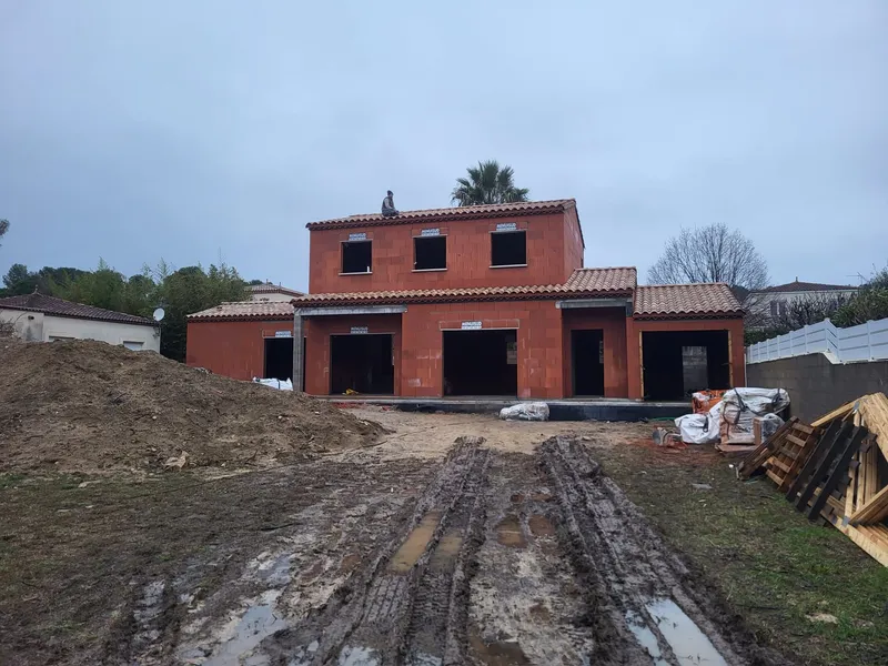 Maison en briques et terrasse. Construction à étage avec terrasse couverte donnant sur le terrain.